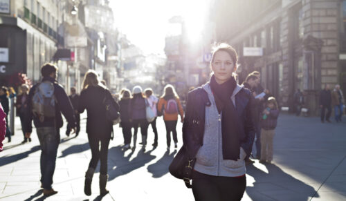 Urban girl standing out from the crowd at a city street.