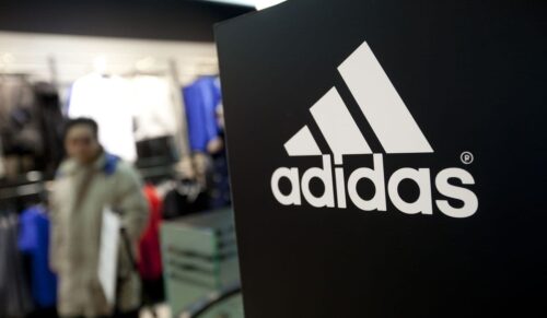 The Adidas AG logo is displayed as customers browse products at the company's store in Beijing, China, on Saturday, Feb. 18, 2012. Adidas is expected to annouce earnings on March 7. Photographer: Nelson Ching/Bloomberg