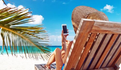 Young woman in hat with mobile phone at the beach