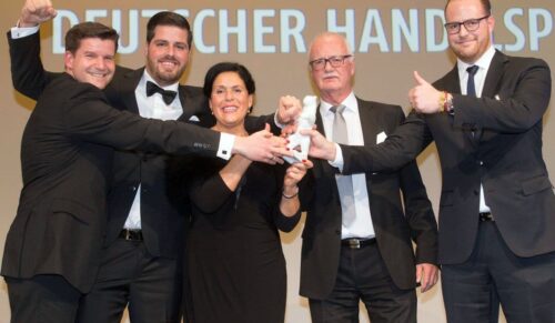 DEUTSCHLAND, BERLIN, 18.11.2015, Deutscher Handelskongress und Kongressmesse Retail World im Maritim Hotel, Gala-Dinner mit Verleihung des Deutschen Handelspreises, Marc Leinweber (r.), Aktiv-Schuh Handelsgesellschaft mbh, Preistraeger in der Kategorie „Managementleistung Mittelständisches Unternehmen“ posiert zusammen mit seiner Familie (Vater Hans, Mutter Maria, Bruder Timo) und dem Vertriebsleiter Jens Holland mit dem Porzellan-Baeren  © Joerg Sarbach