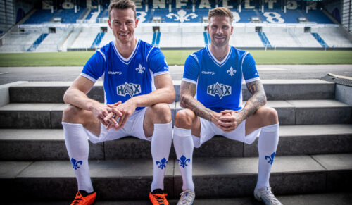 Die Darmstadt 98-Spieler Christoph Zimmermann und Tobias Kempe präsentieren das neue Heimtrikot mit dem Haix-Schriftzug. (Foto: Haix)